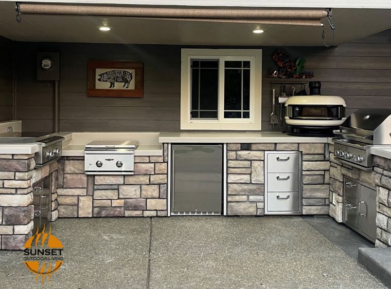 Outdoor kitchen with white countertops, grill, pizza oven and more. stone brick facings in muted tones of eggplant, taupe and grey, stainless steel appliances