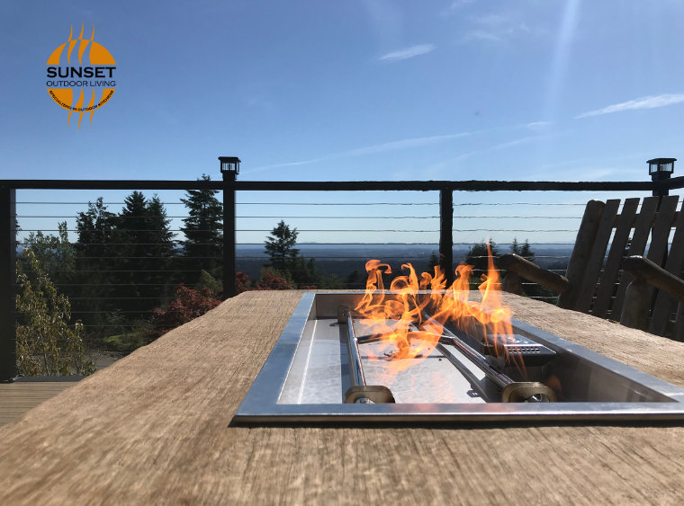 large tabletop fire feature with wood top on high deck with gorgeous view of the trees, sky and horizong